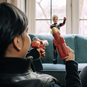 Photorealistic image of the NERF Power Moves Marvel Avengers Captain Marvel Photon Blast toy set. Colorful packaging showcasing a dynamic scene of Captain Marvel with a young girl, surrounded by vibrant Marvel-themed elements.