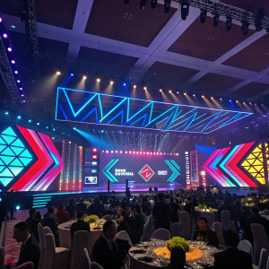 A vibrant scene from the East Tech West gala dinner in Guangzhou. Modern stage design with LED screens and geometric shapes in vibrant colors. A diverse audience of various genders and ethnicities.