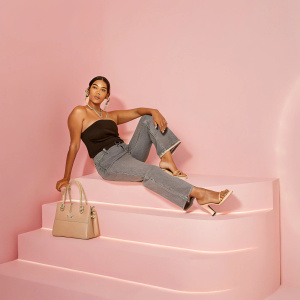 Janina Gavankar, an actress, poses in a black cocktail dress and a casual blouse with jeans. Against a bright, white backdrop. High resolution.