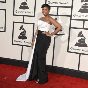 Jennifer Hudson, stunning in a black and white gown, graces the Grammys red carpet. The dress features a dramatic white top and structured black skirt. Backdrop is filled with Grammy logos