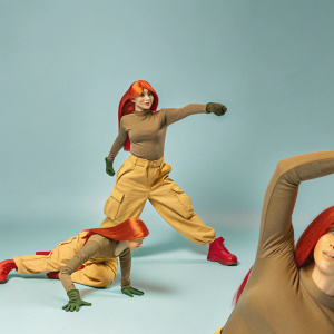 Kim Possible, an animated superhero, poses dynamically in various stances. Wearing a brown top and green pants with orange hair. Set against a dark grey backdrop.