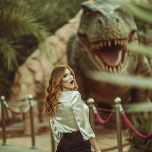 Ariana Madix at Hollywood Walk of Fame unveiling. Wearing a white silk blouse and black pants. T-Rex statue in background.