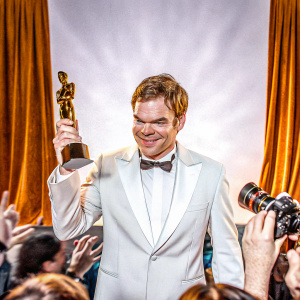 Michael C Hall accepting award. Onstage at a glamorous Hollywood event. Dark velvet backdrop