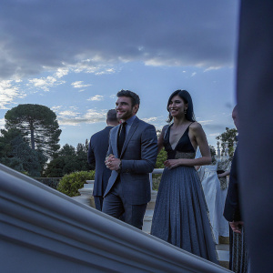 Richard Madden and Gemma Chan at a charity event. Clear blue sky and green trees in the background