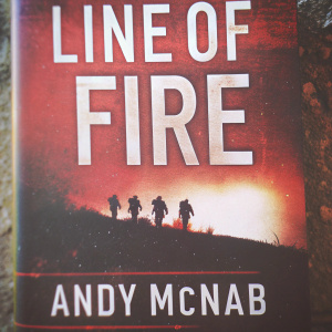 Book cover for 'Line of Fire' by Andy McNab. The cover is predominantly red with silhouettes of soldiers on a rugged terrain. The title and author's name are in bold white letters.