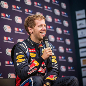 Sebastian Vettel, young and smiling, sits for an interview. Numerous sponsors' logos in the background.