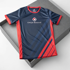 Illustration of Chico Resolve's new athletic t-shirt. Shiny surface, modern design with navy blue and red accents. Logo centered on chest. T-shirt placed on matching gray packaging box, minimalist neutral gray backdrop.
