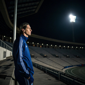 Fernando Torres in a blue tracksuit, looking grim. Empty stadium behind him, night time