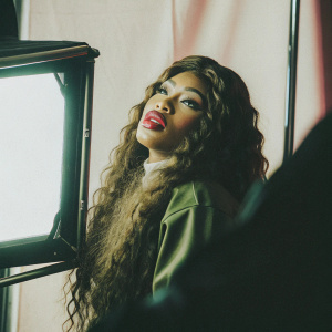 Close-up portrait of Nicki Minaj. Wearing bright red lipstick, long curly hair. Pink studio backdrop.