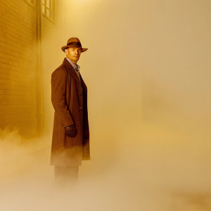 Captain Sean Renard, portrayed by Sasha Roiz, standing confidently in front of a dimly lit, foggy alleyway. Wearing a dark coat and hat.