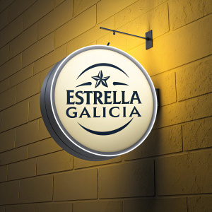 Circular Estrella Galicia logo, glowing against a bright yellow background. Simple sans-serif font, modern and sleek.