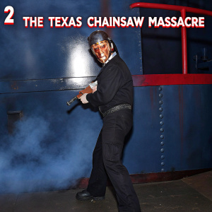 DVD cover for 'The Texas Chainsaw Massacre 2'. Dennis Hopper in character, standing menacingly against a dark, industrial backdrop. Smoke and rusty metal surroundings.