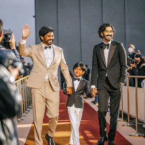 Saroo Brierley, Sunny Pawar, and Dev Patel at a glamorous movie premiere. Red carpet event with flashing cameras.