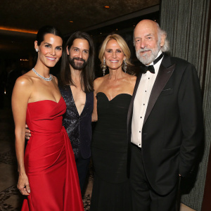 Angie Harmon, Wendy Bellissimo, Joe Bellissimo, and Mick Fleetwood at a glamorous indoor gala. Elegant attire, dark and textured background.