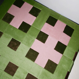 A detailed snapshot of a Minecraft-inspired carpet. Close-up view of the blocky design featuring a mix of earthy tones. The pixelated pattern forms a grid-like texture.