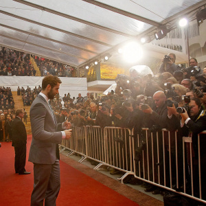 Jamie Dornan signing autographs at the Cannes Film Festival. Crowded red carpet, fans and paparazzi in the background.
