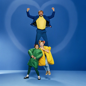The Powerpuff Girls and Dr. Ken, in an action-packed pose. Vibrant pink heart-shaped backdrop. Girls are positioned below, with Dr. Ken towering above.