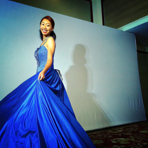 Choi Yeo-jin, smiling at the Grand Opening of a Luxury Boutique. She is dressed in an elegant royal blue gown with intricate details. White backdrop with boutique's logo