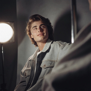 Justin Bieber, wearing a casual denim jacket, mid-shoot photo. Studio setting