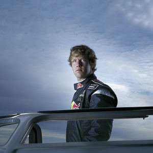 Sebastian Vettel, driver, intense look. Red Bull Racing jacket. Blue backdrop with sponsors logos.