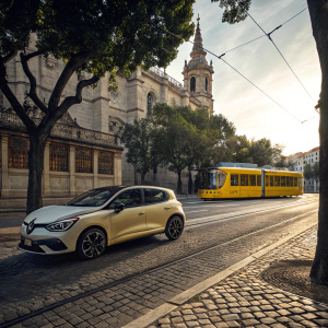 Renault Clio RS Line parked on a cobblestone street. Beside a historic building. Tram passing by in the background.