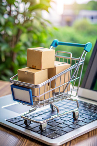 E-commerce. Paper boxes in shopping cart on keyboard and sales data economic growth graph on computer screen, online shopping and payments, banking, buying and selling services online on network.