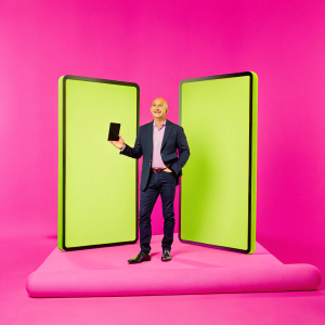 Jeff Bezos, Amazon founder, presenting the Kindle e-reader. A futuristic stage with LED screens behind him showcasing device features.