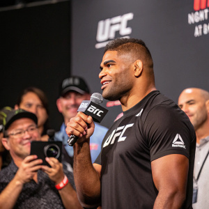 Alistair Overeem at a UFC press conference. Wearing a UFC branded shirt, speaking into a microphone.