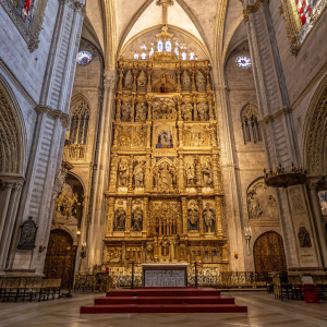 Inside Seville Cathedral, the intricate golden altar stands out with detailed sculptures and religious figures. Richly adorned with gold and intricate designs, depicting various religious scenes.