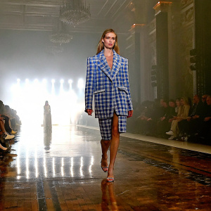Rosie Huntington-Whiteley, strutting on the New York Fashion Week runway. Wearing a striking blue and white chequered ensemble, she commands attention.