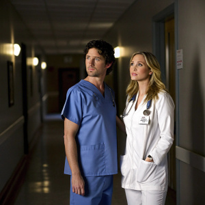 JD and Carla from Scrubs standing in the dimly lit hospital corridor. JD in blue scrubs, Carla in white nurse's uniform.