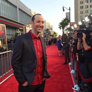 Tony Hale at the premiere of Alvin and the Chipmunks: The Road Chip, standing on a red carpet. Dark blazer and red shirt, smiling widely