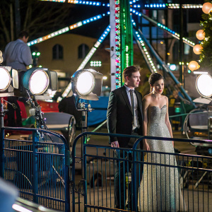 Robert Pattinson and Camilla Belle, at a glitzy event. Festive backdrop, colorful lights and camera flashes