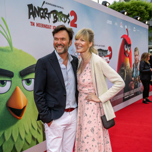 Tobey Wilson and Sabrina Gehrmann at 'Angry Birds 2' premiere. Smiling, standing on a red carpet, movie poster backdrop.