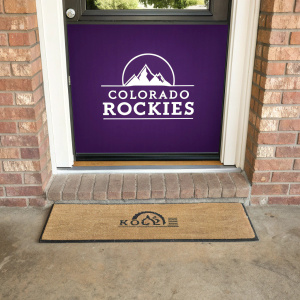 A Colorado Rockies logo on a purple backdrop with modern font. The doormat is beige with a rustic brick wall in the background.