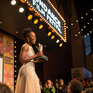 Thuso Mbedu accepting award at Sundance Film Festival. Grinning widely while holding trophy.