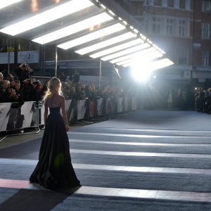 Annabelle Wallis at the 'Grimsby' premiere. Walking down a bustling red carpet. Crowds cheering. Neon lights reflecting off the glossy black floor-length gown.