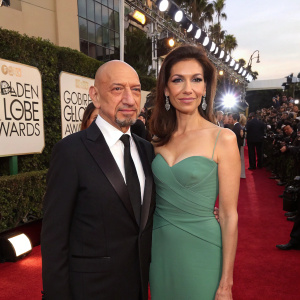 Ben Kingsley and Daniela Lavender at the Golden Globe Awards. Red carpet with flashing lights and paparazzi in the background.