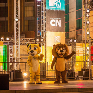 Cartoon Network Hall of Game Awards event. Mascot costumes in cheetah-like and leonine designs. Friendly and fierce expressions. Branded backdrop