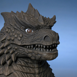 Close-up of a meticulously crafted Baragon figurine from the Godzilla series. The creature's rough, earthy brown skin and fierce expression are prominently displayed against a simple, neutral backdrop.