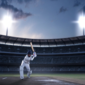 Virat Kohli, in a focused batting stance. A cricket stadium with cheering fans in the background. The field is blurred, highlighting Kohli's concentration.