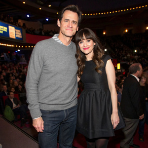 Jim Carrey and Zooey Deschanel at a film festival. Carrey in a casual gray sweater and dark pants, Deschanel in a chic black dress. Crowded venue, vibrant atmosphere.