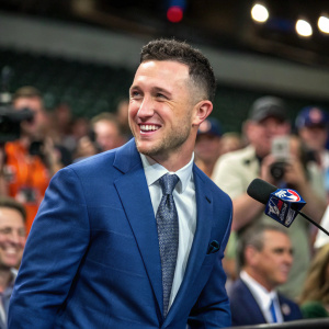 Alex Bregman, Houston Astros player, wearing blue suit and tie. Nervous smile at press conference. Audience in background.