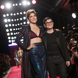 Selma Blair and Christian Siriano on the New York Fashion Week runway, surrounded by vibrant lights and cameras.