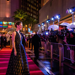 Hilary Swank, in a stunning black dress with geometric patterns, at the Golden Globe Awards. Crowded, vibrant red carpet scene.
