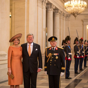 Joachim Gauck, the former German President, alongside his partner Daniela Schadt, and the Dutch Royal couple, King Willem-Alexander and Queen Maxima, stand formally in a grand hall. Guarded by a soldier in ceremonial uniform. Ornate building with columns in the background.