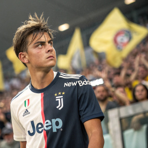 Paulo Dybala, soccer player, intense gaze, wearing New Balance jersey with large logo. Messy hair, surrounded by cheering fans.