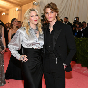Courtney Love and Jordan Barrett at the Met Gala. Courtney, blonde, silver shirt and black dress. Jordan, nicely dressed in black suit. Celebrity-filled red carpet.