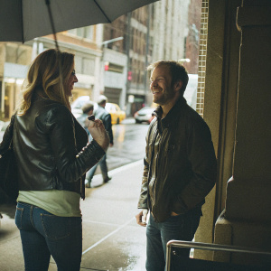 Jenna Fischer and Lee Kirk at the 2016 Tribeca Film Festival. Jenna in a black leather jacket and jeans, Lee in casual attire. Backdrop is bustling city street