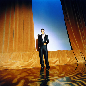 Jakob Ingebrigtsen, in a sleek black tuxedo, accepting an award at the Sportsman of the Year ceremony. Dark velvet background, spotlight on him